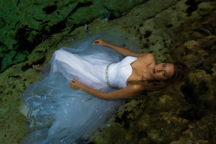 Bride lying on the edge of a cenote in Mexico