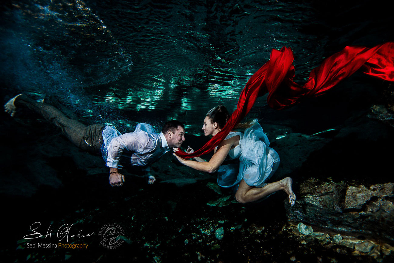 Bride and groom playing in the magic underwater setting of a cenote 